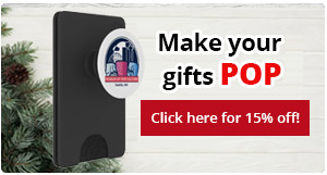 A PopScokets PopWallet+ on a white wood background, with fir tree branches and pinecones in the bottom left corner. Overlaid text says, "Make your gifts POP. Click here!"