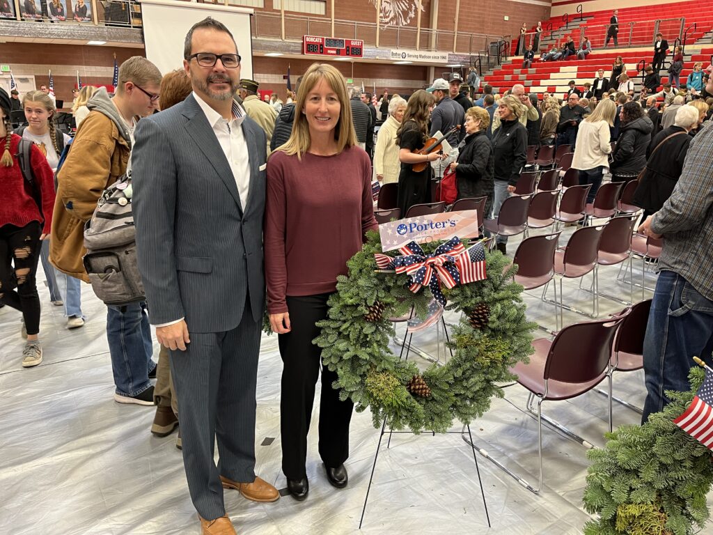 Mark and his wife standing next to the Porter's Office Products wreath at the Veterans Day event hosted by the Rexburg area Chamber of Commerce.