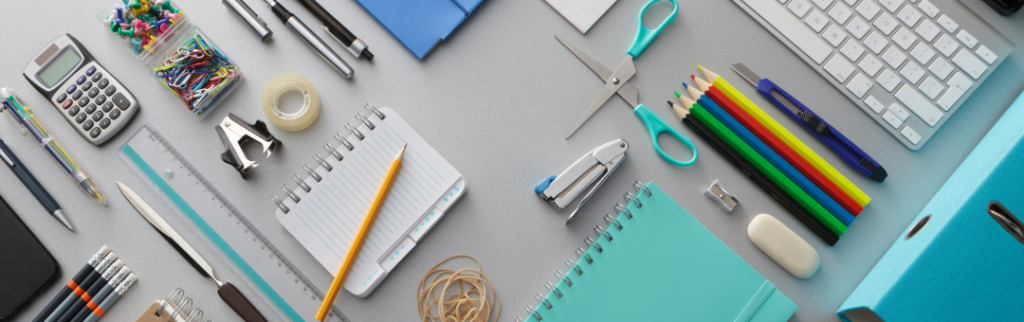 An array of colorful office supplies on a gray desk.