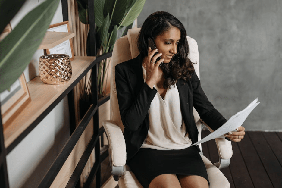 Businesswoman reviews documents while talking on phone in modern sustainable office. Photographer: Pavel Danilyuk